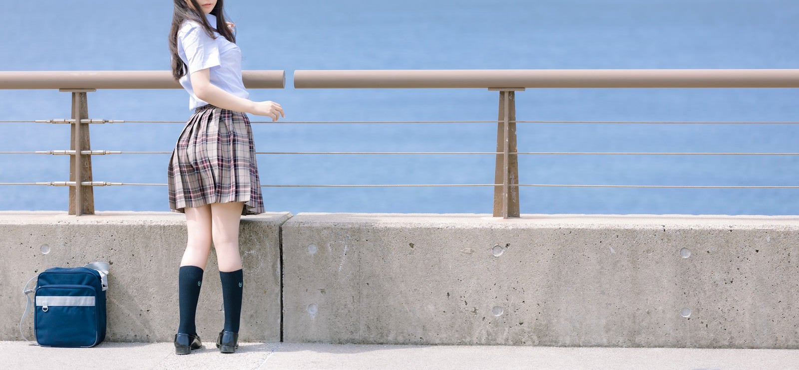 「防波堤前で振り返る女子高生」の写真［モデル：石投げて美奈代］