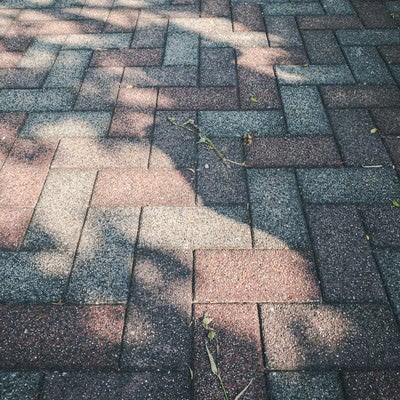 影が伸びるレンガブロック敷きの地面の写真