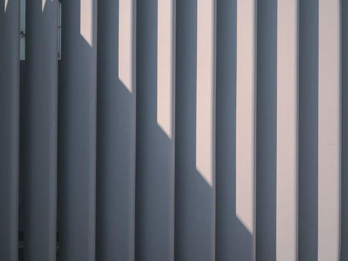 囲いのフェンスにかかる影のテキスチャーの写真