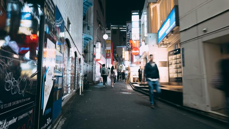 夜の道玄坂小路に並ぶ店舗と人々の風景の写真
