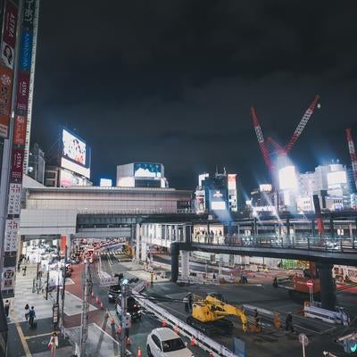 渋谷駅南口の工事現場と輝くネオンの写真