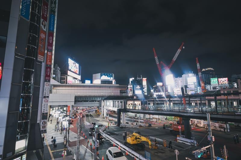 渋谷駅南口の工事現場と輝くネオンの写真