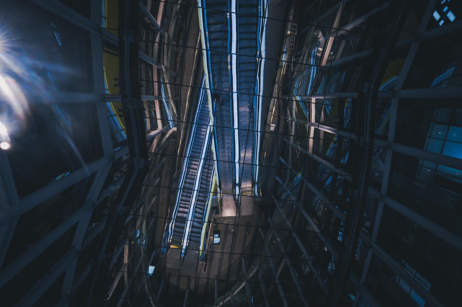 「ガラス天井に映るエスカレーターの反射アート」の写真