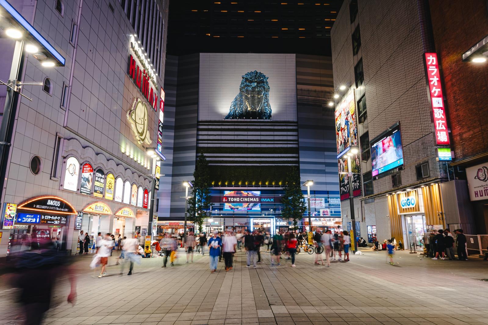「新宿シネシティ広場に集う人たちとゴジラ（夜間）」の写真