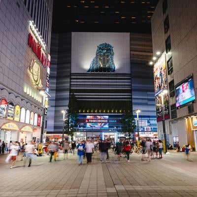 新宿シネシティ広場に集う人たちとゴジラ（夜間）の写真