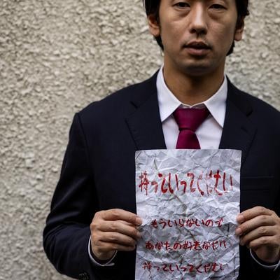 無言で怪しい文書を掲げるビジネスマンを映した一枚。の写真