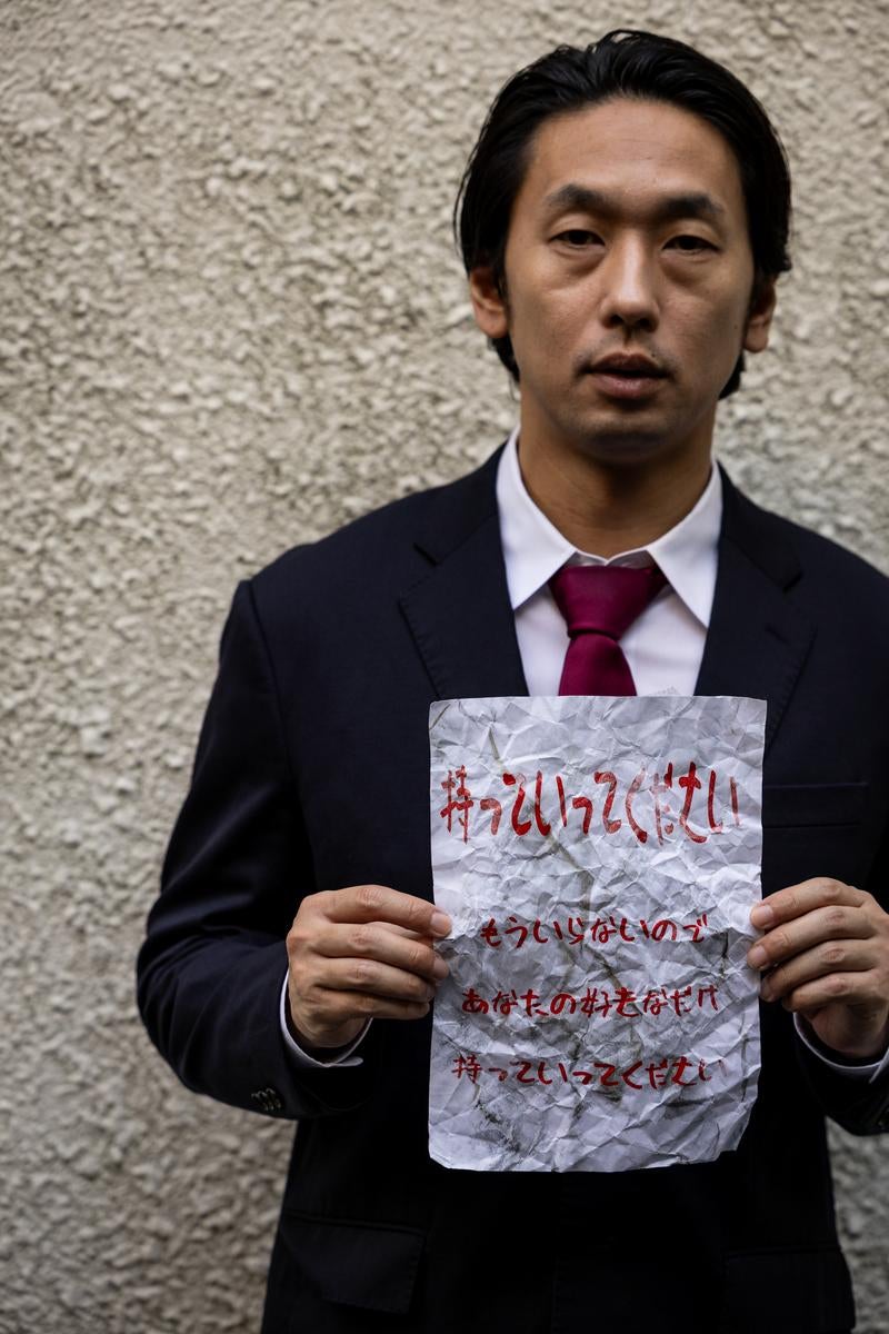 「無言で怪しい文書を掲げるビジネスマンを映した一枚。」の写真［モデル：大川竜弥］