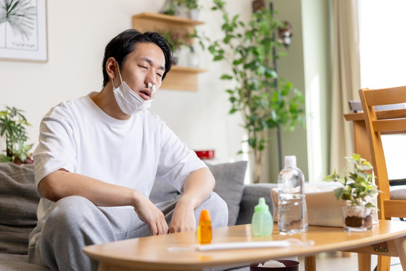 「鼻にティッシュを詰めて項垂れる男性」の写真［モデル：大川竜弥］