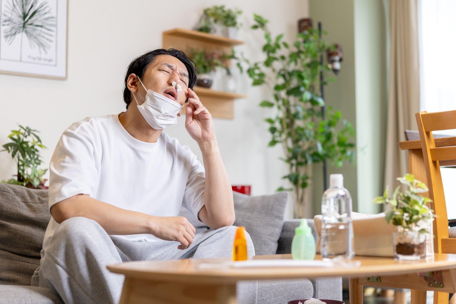 「両方に鼻栓しながらマスクもする花粉症で苦しむ男性」の写真［モデル：大川竜弥］