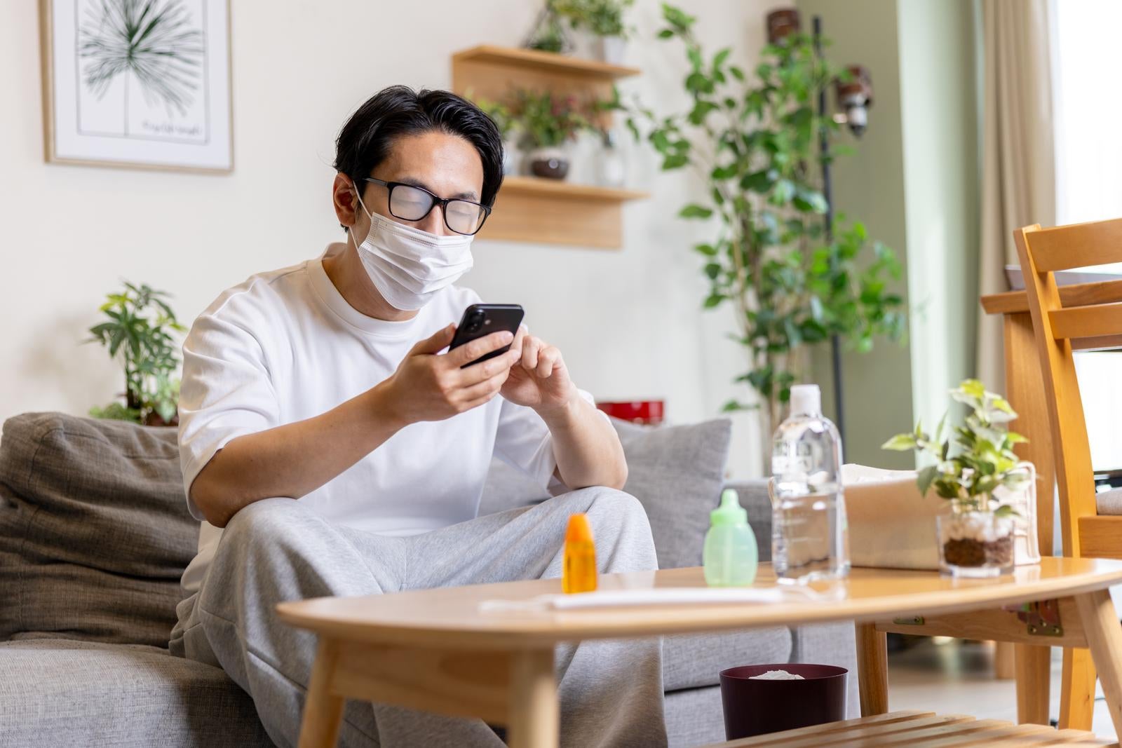 「マスクでメガネが曇ってスマホが見えない男性」の写真［モデル：大川竜弥］