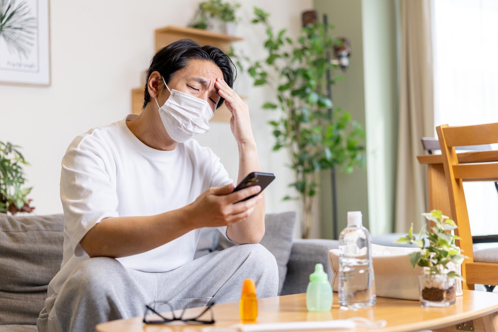 「アレルギー性鼻炎がつらくて部屋の中でもマスクをつける男性」の写真［モデル：大川竜弥］