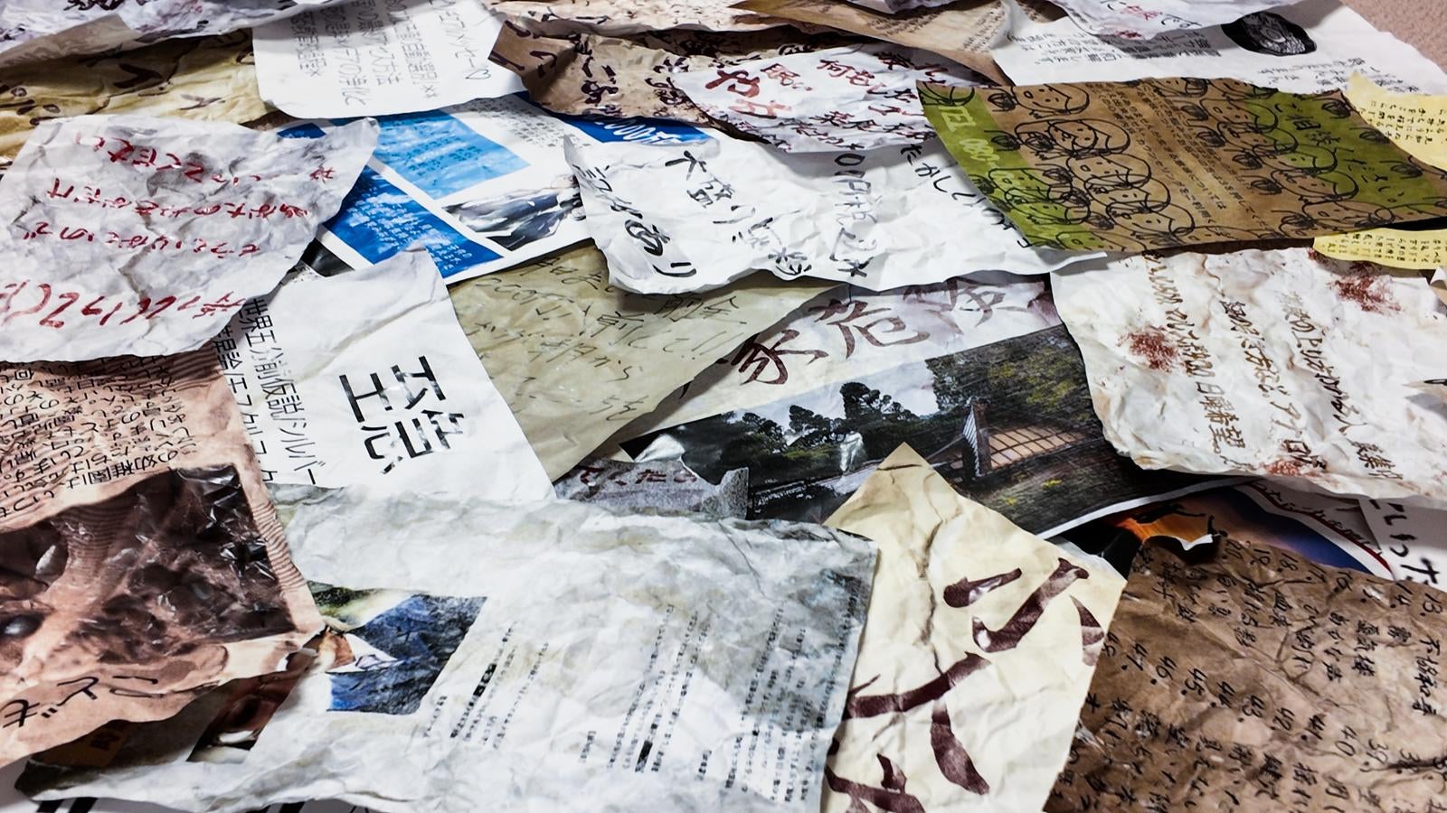 「複数の怪文書が床に広がる異様な構図」の写真