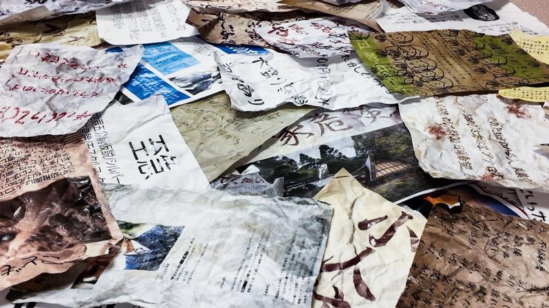複数の怪文書が床に広がる異様な構図の写真