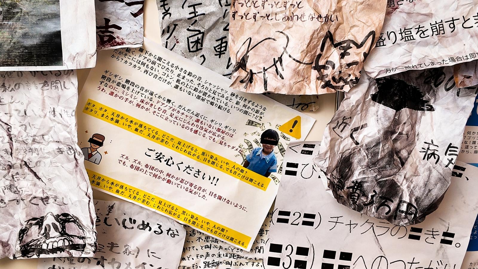 手書き文字やイラストが書かれた怪文書の紙片が折り重なって散乱している