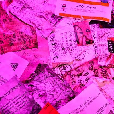 ピンクのライティングで演出された不気味な手書き文書とメモの山の写真