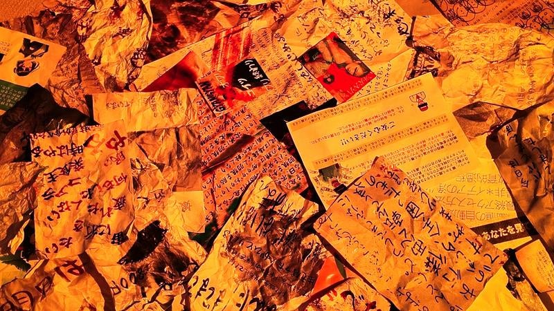 オレンジ照明で照らされた怪文書の山の写真