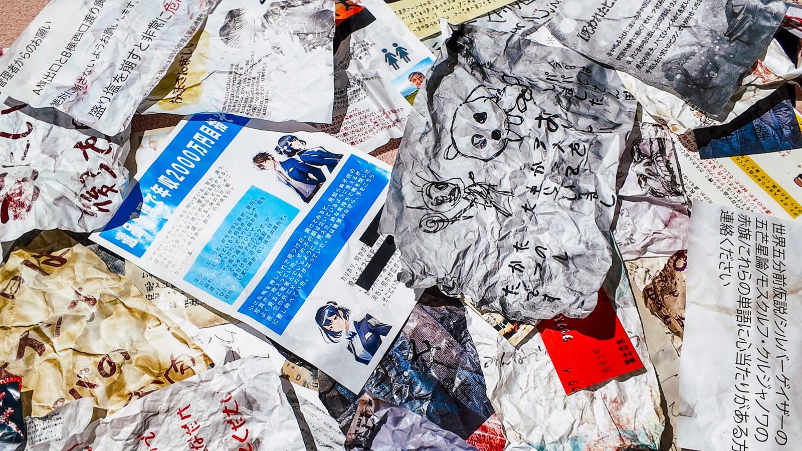 床に散乱した新聞紙と雑誌の破片が無造作に重なっている