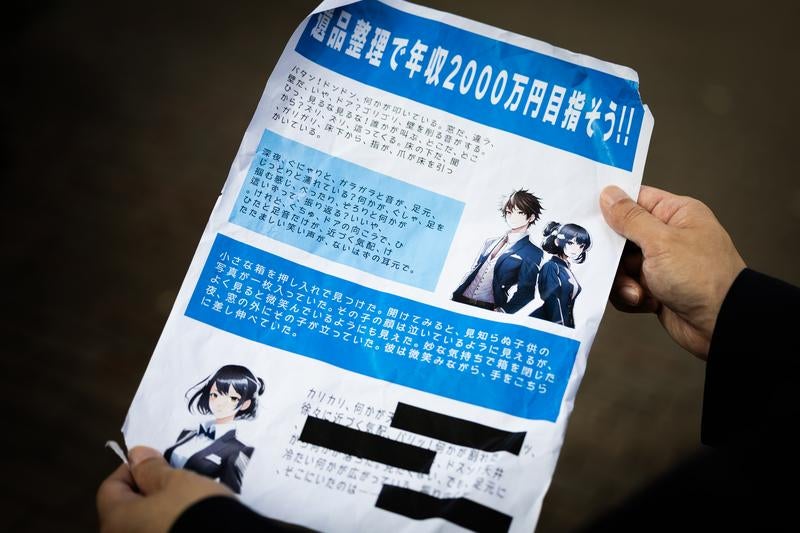 怪しすぎる高収入勧誘チラシを持つ人物の写真