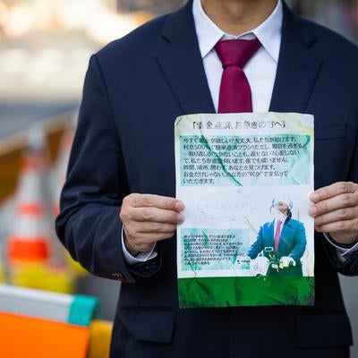 街角で怪文書を堂々と掲げるサラリーマンの写真