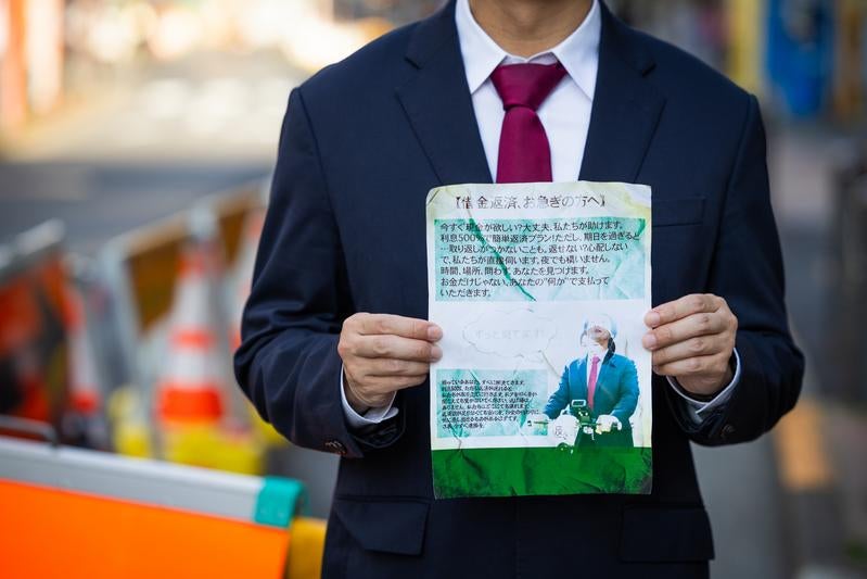 街角で怪文書を堂々と掲げるサラリーマンの写真