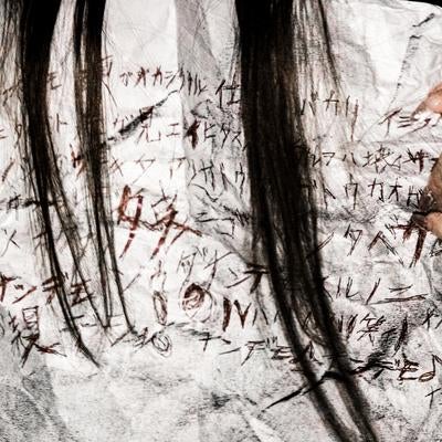 怪文書を握りしめる長髪女性の恐怖の写真