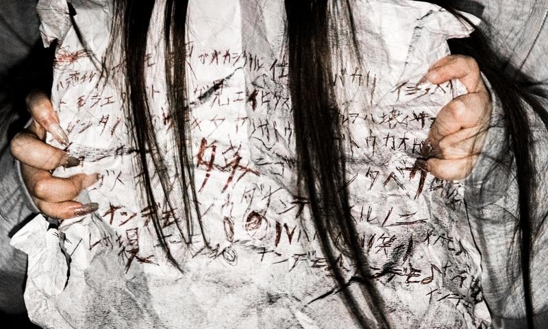 怪文書を握りしめる長髪女性の恐怖の写真