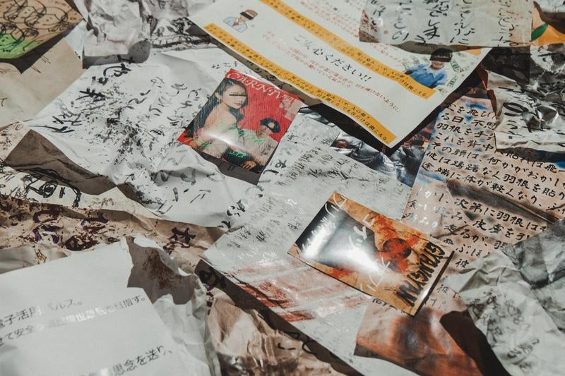 床に散乱した手書き文字のビラの写真