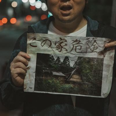 「この家危険」と書かれた怪文書を掲げる男性の写真