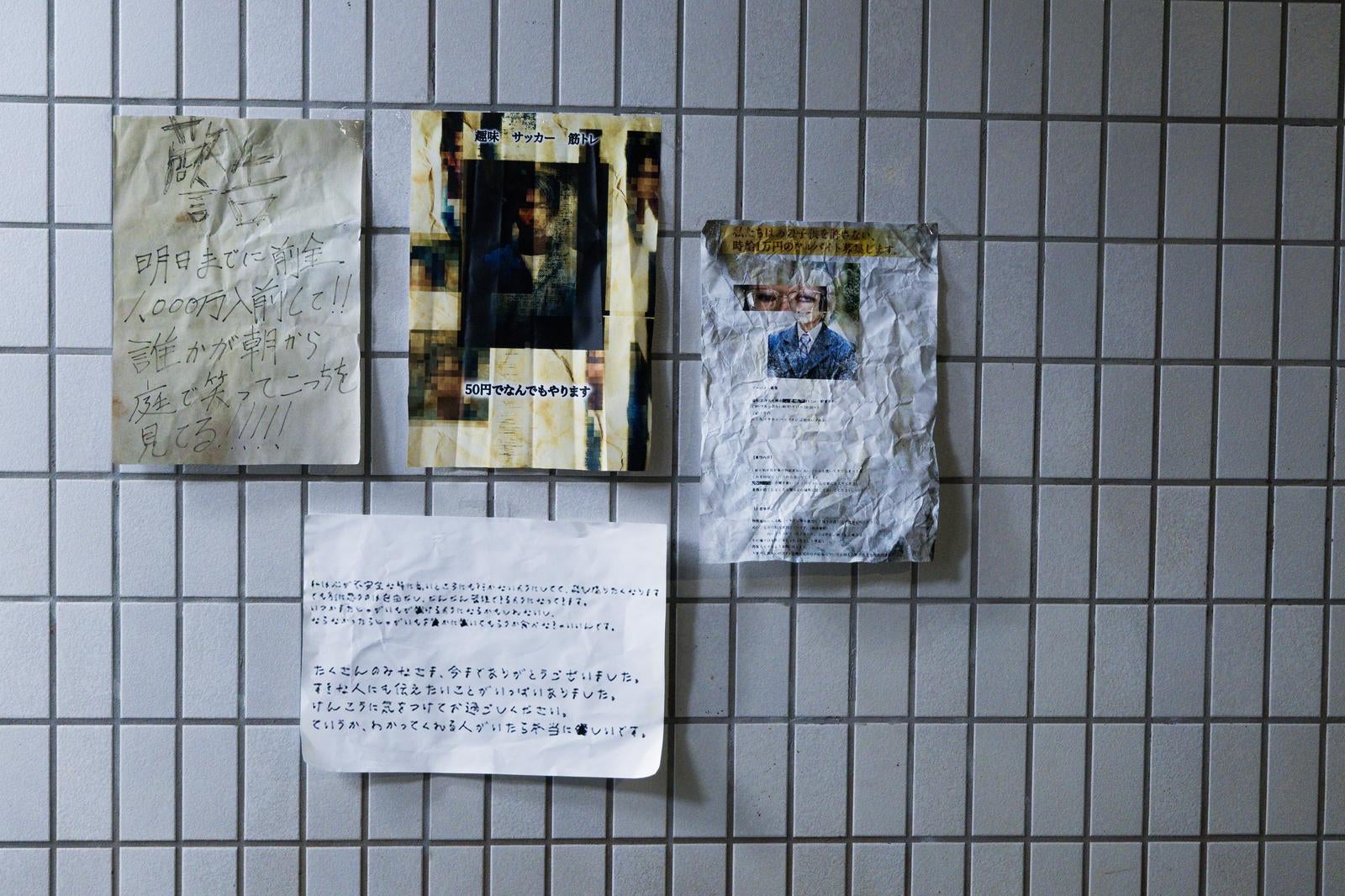 「タイル壁に浮かぶ怪文書の掲示板」の写真