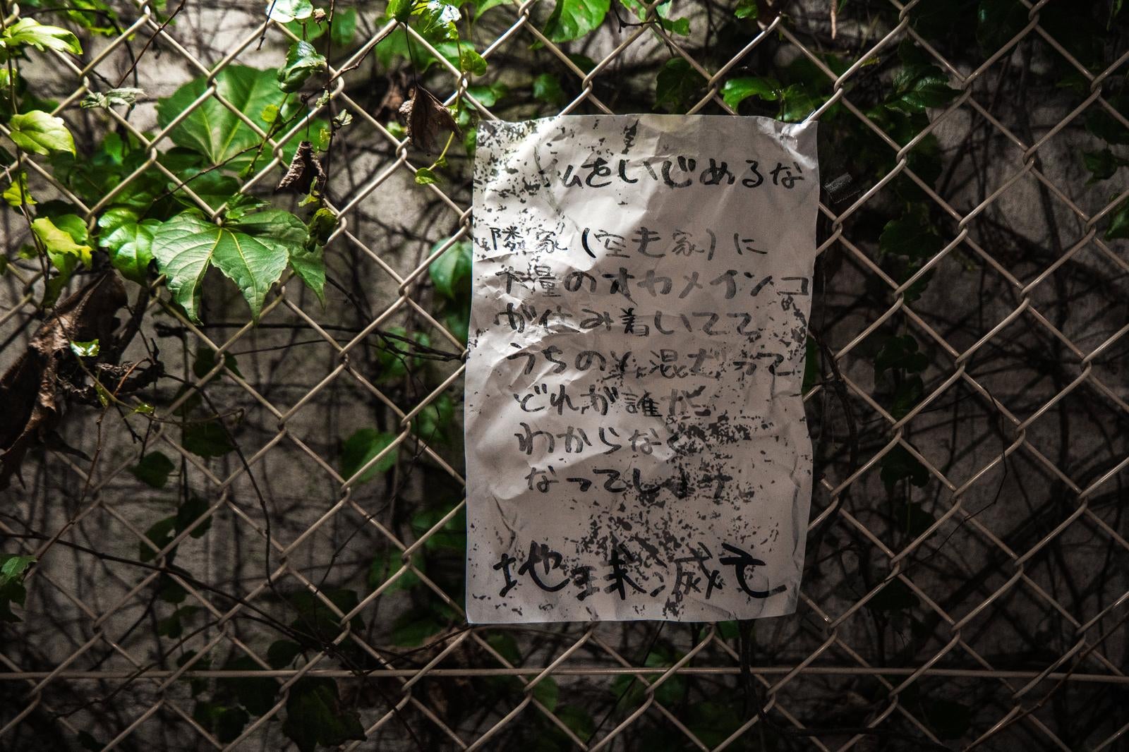 「夜のフェンスに貼られた恐怖の怪文書」の写真