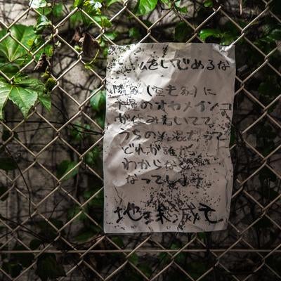 夜のフェンスに貼られた恐怖の怪文書の写真