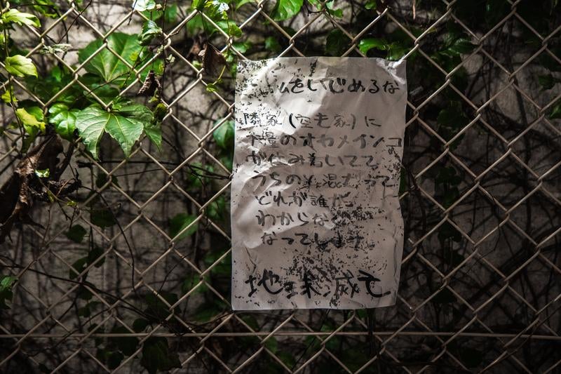 夜のフェンスに貼られた恐怖の怪文書の写真