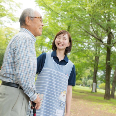 高齢者の男性と公園散歩を楽しむ介護士の女性の写真