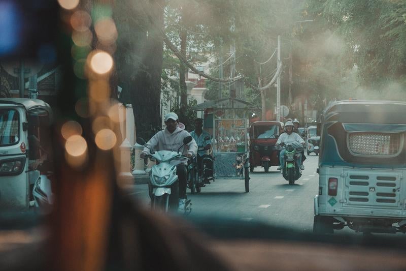 カンボジアの都市部でよく見られるトゥクトゥクが走るの写真