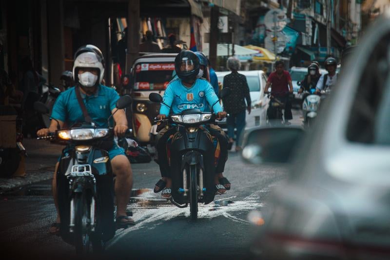 細い市街地の通りをバイクが走り抜ける様子の写真