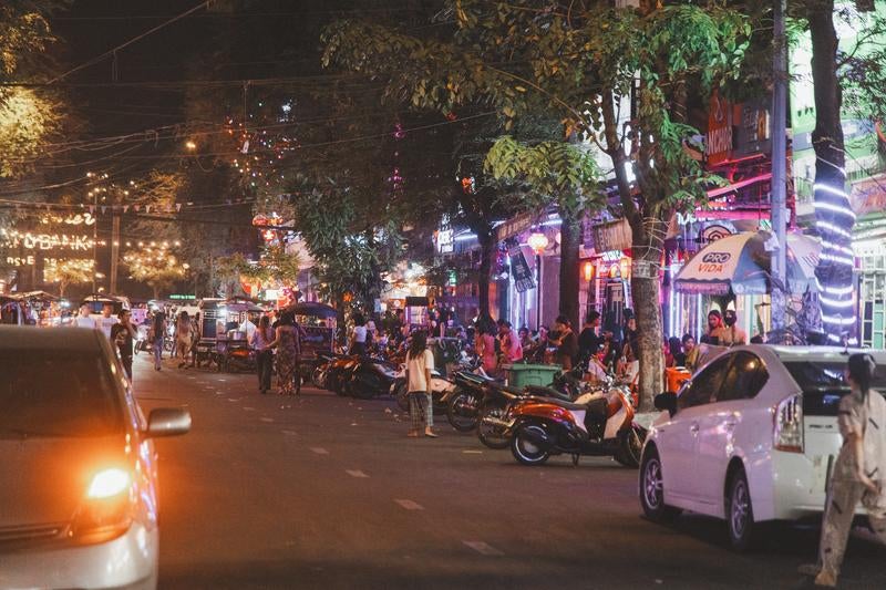 カンボジアの繁華街にある屋台や飲食店が並ぶネオンが輝く夜の通りの写真