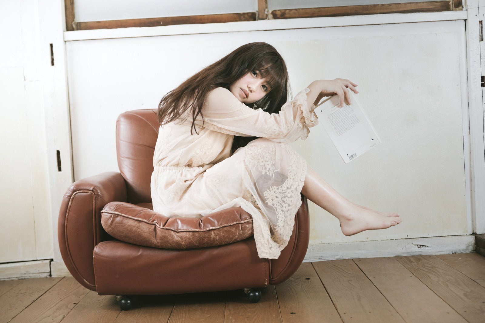 「一人掛けソファーを大胆に使う読書女子」の写真［モデル：河村友歌］