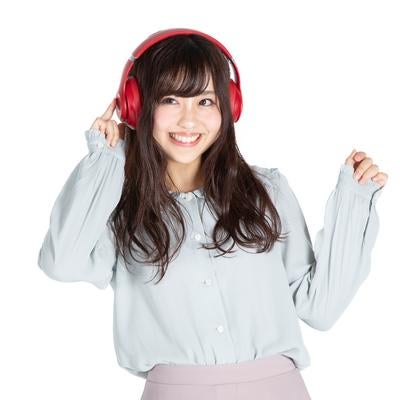 赤いヘッドフォンで音楽を楽しむ笑顔の女性の写真