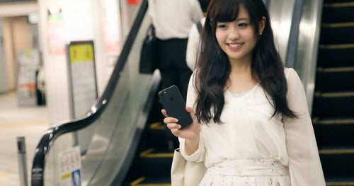 財布や定期券を出さずにスマートフォンで駅の改札を出る女性の写真