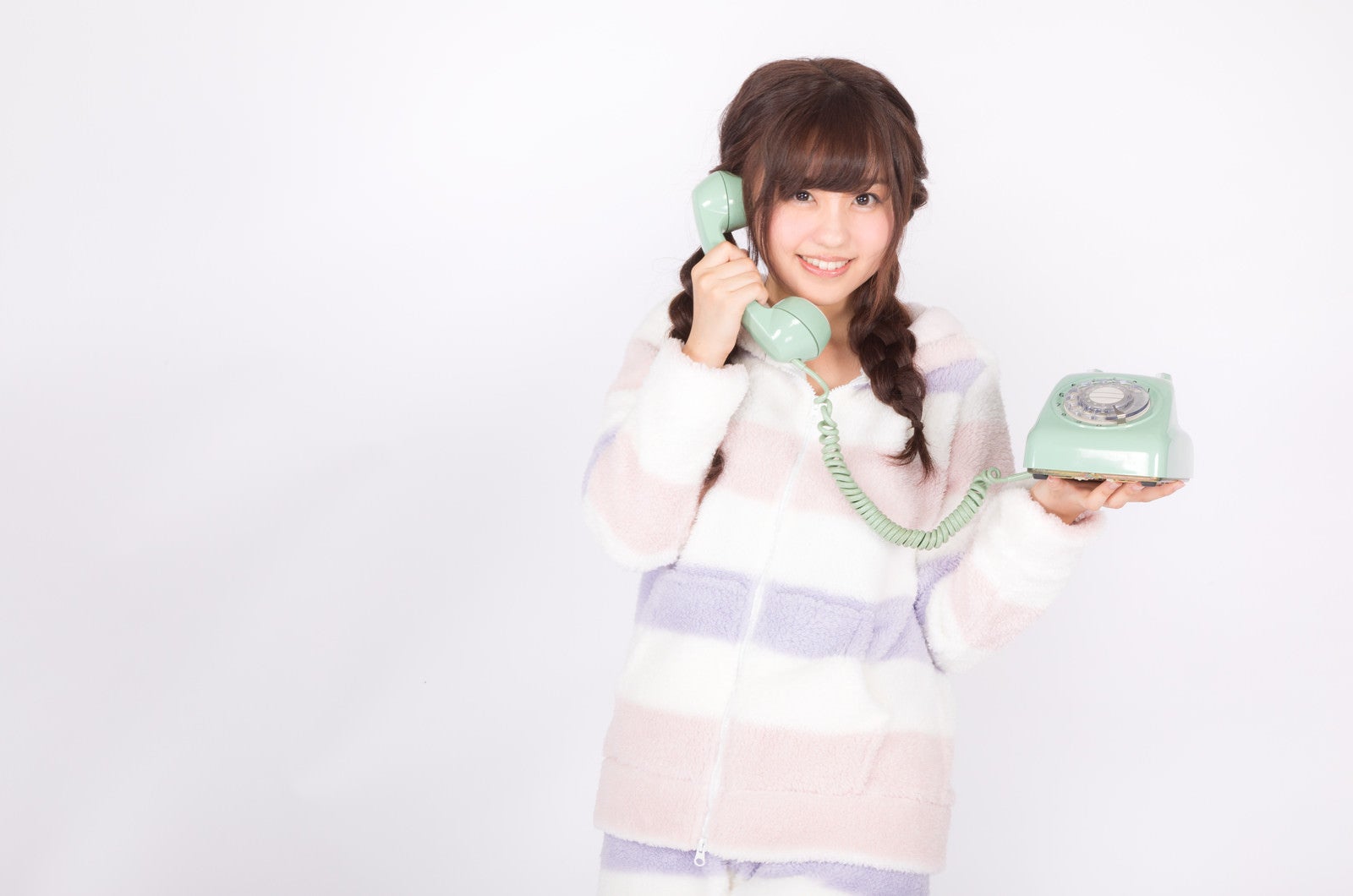 「ダイヤル式の電話を片手に通話する女性」の写真［モデル：河村友歌］