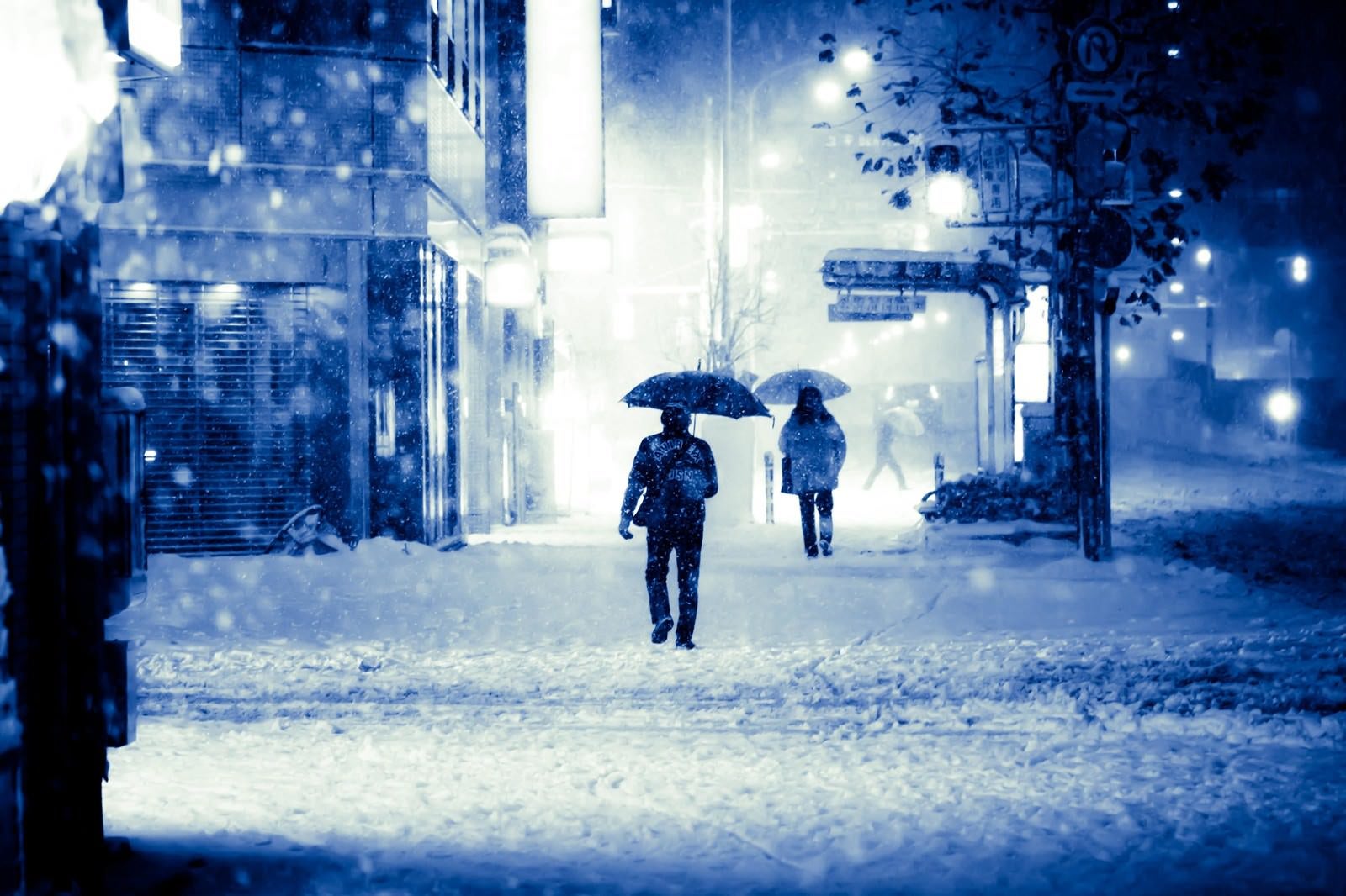 「積雪で電車が止まり傘を差して家路に向かう」の写真