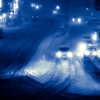 雪が降り積もる夜の幹線道路の写真