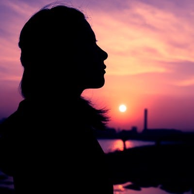 紫色の夕焼けと女性のシルエットの写真