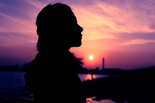 紫色の夕焼けと女性のシルエットの写真