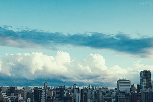 都会のマンションと雲空の写真