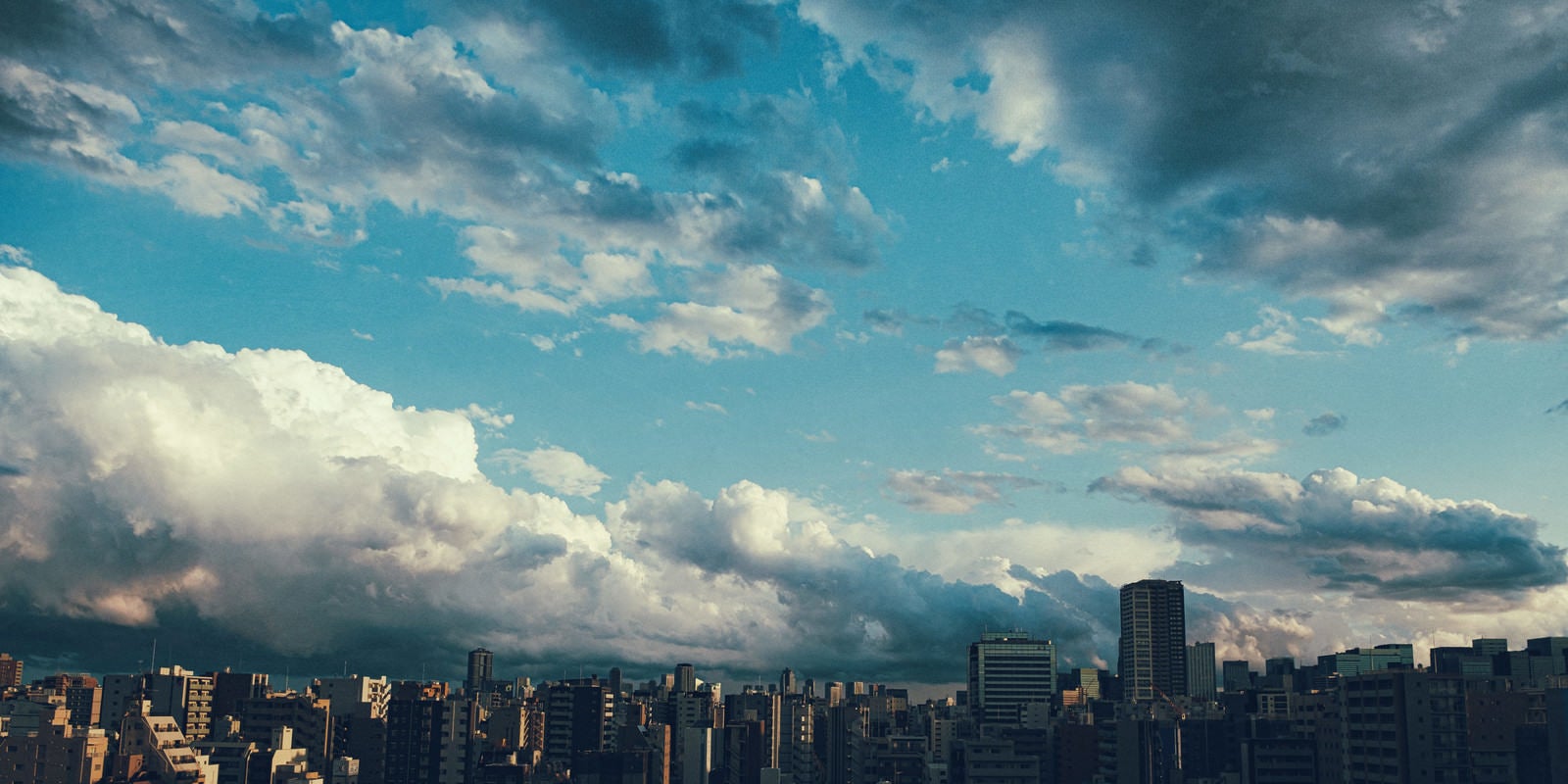 「上空に晴れ間と雨雲の街並み」の写真