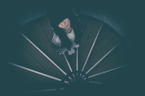 どこまでも続く螺旋階段を見上げる女性の写真