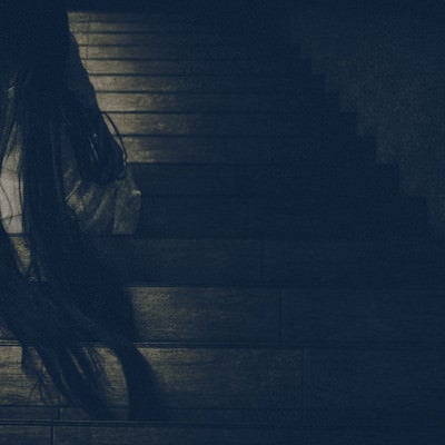 髪の毛を垂れ下げ階段に居座る女性の写真