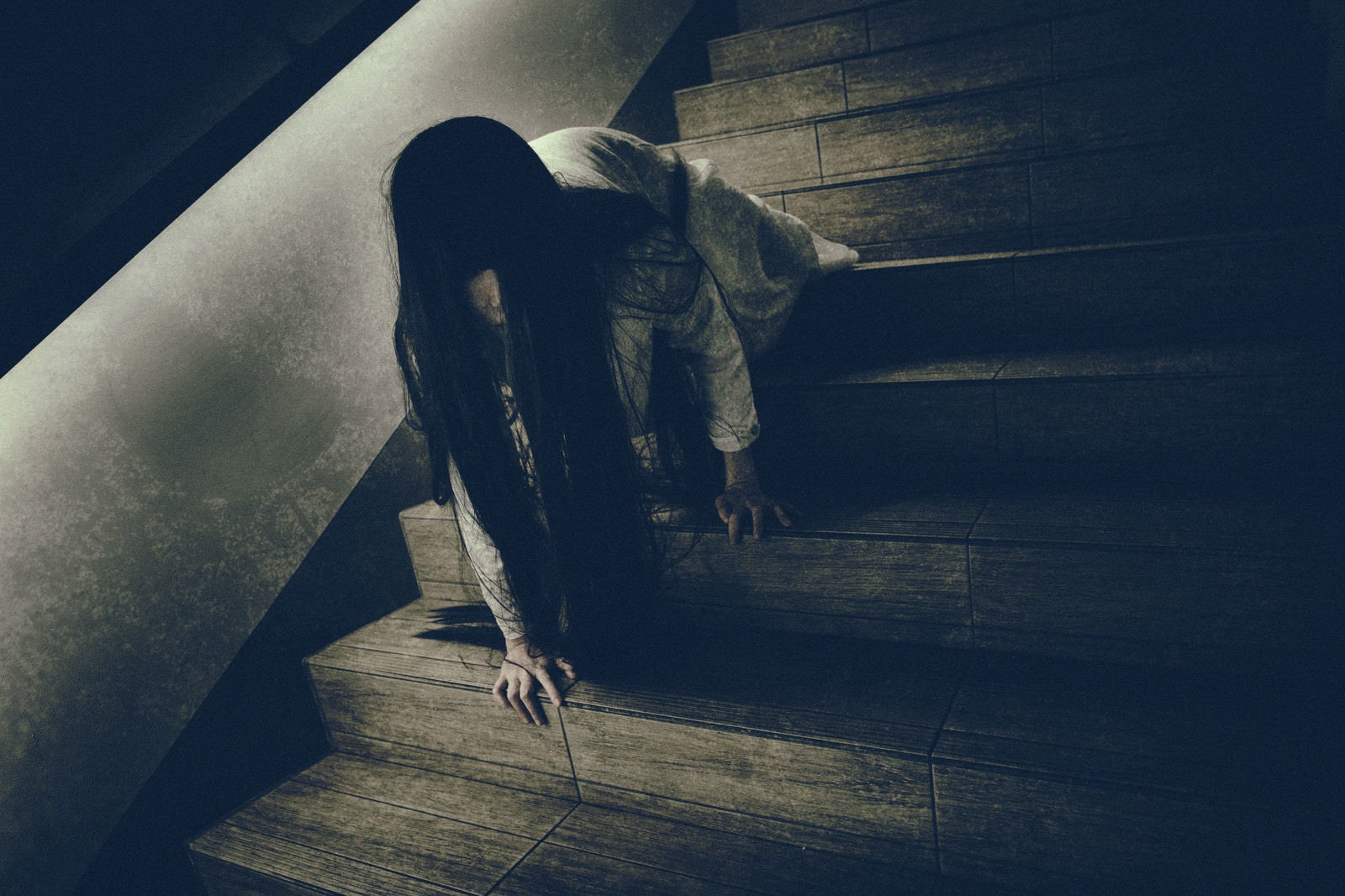 「ゆっくりとこちらを睨みつけようとする階段で蹲る女性」の写真［モデル：緋真煉］