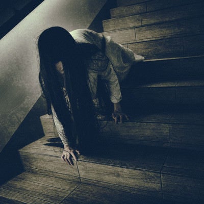 ゆっくりとこちらを睨みつけようとする階段で蹲る女性の写真